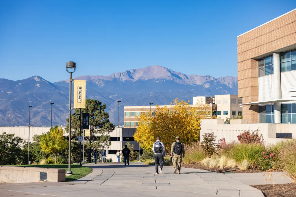 military student walking on campus with mountains in the background